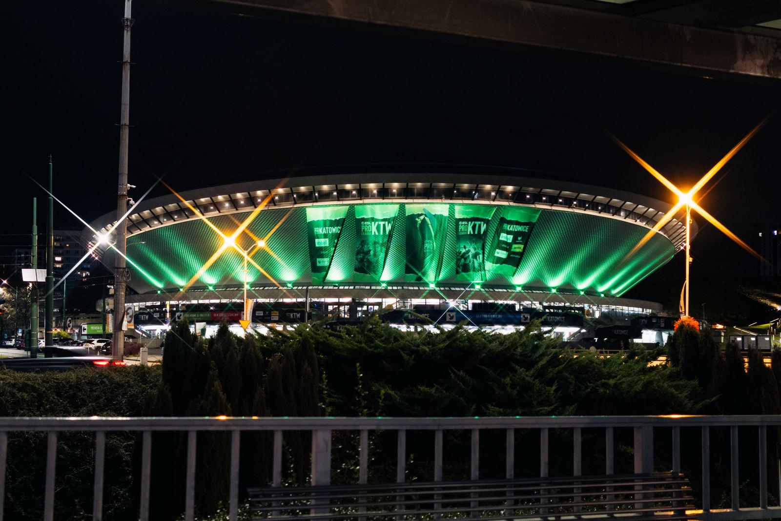 The Spodek arena illuminated in green from the outside at night.